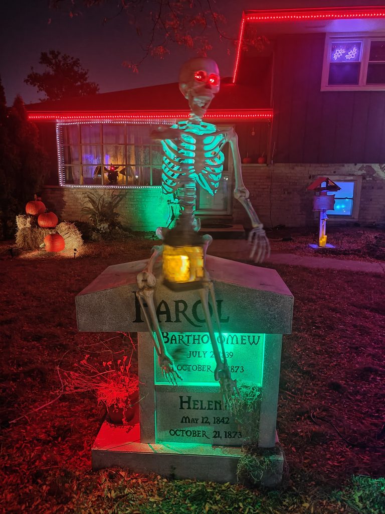 Skeleton holding a lantern while sitting on top of a columbarium
